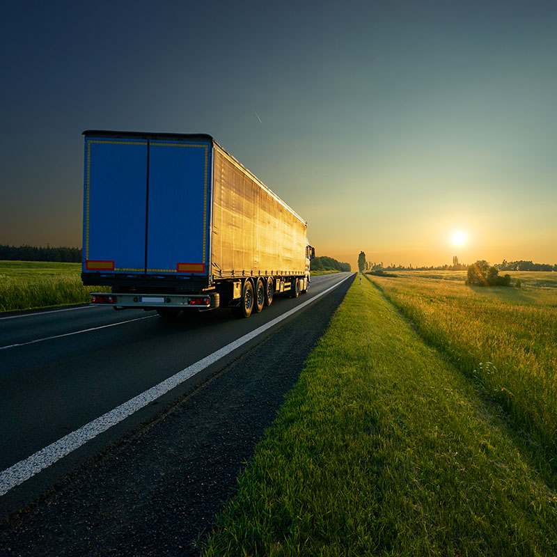 A transport truck driving into the sunrise