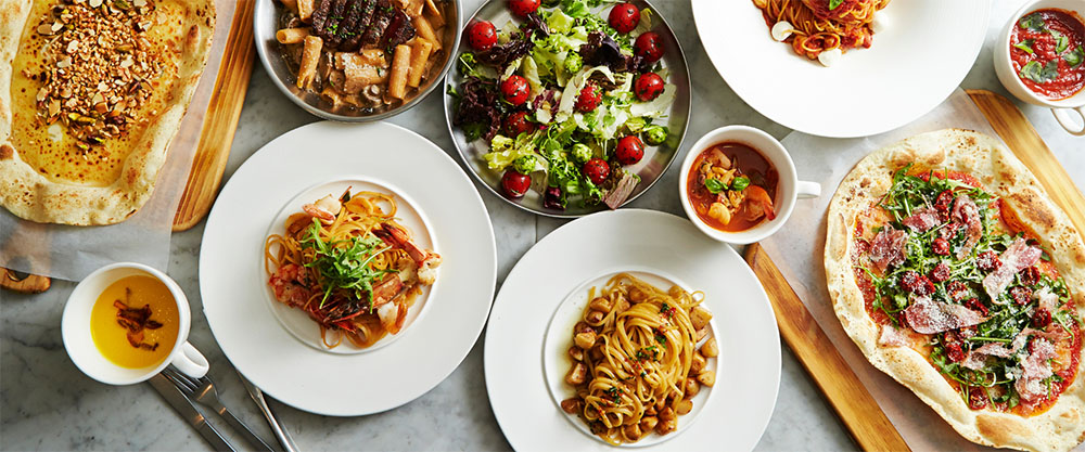 Plates of pasta dishes with a bowl of salad