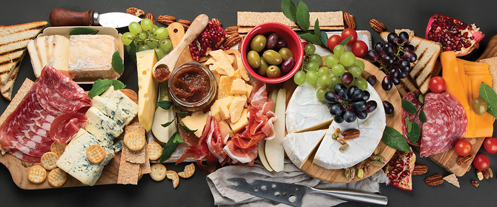 A charcuterie board covered in cheese, meats, and olives