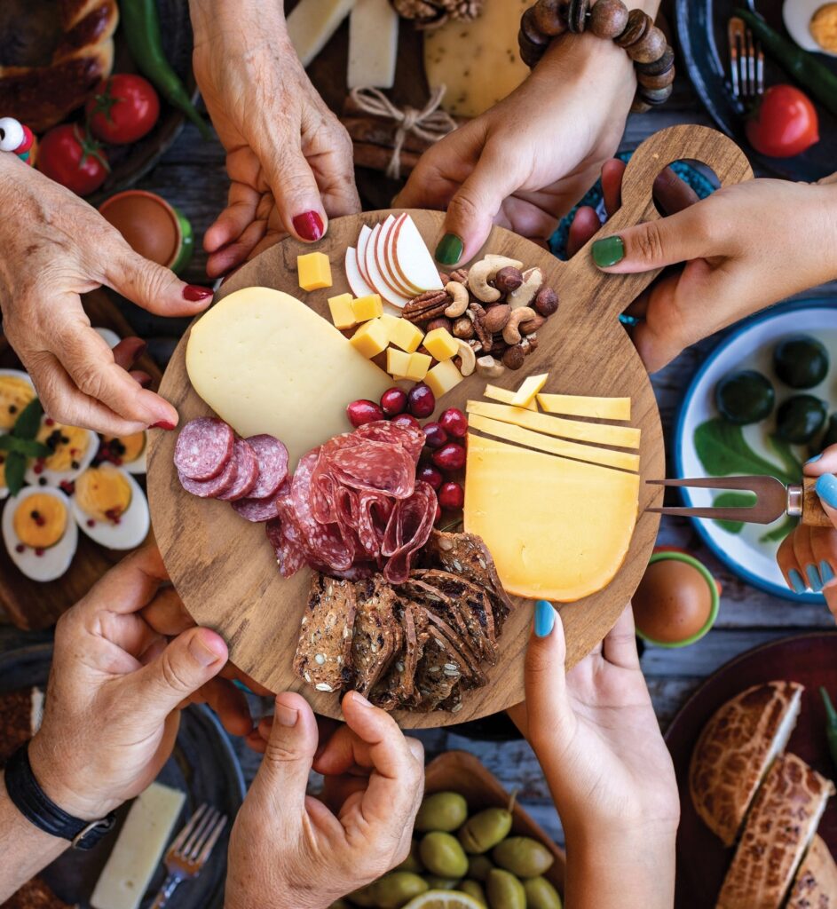 Hands reaching for items on a charcuterie board