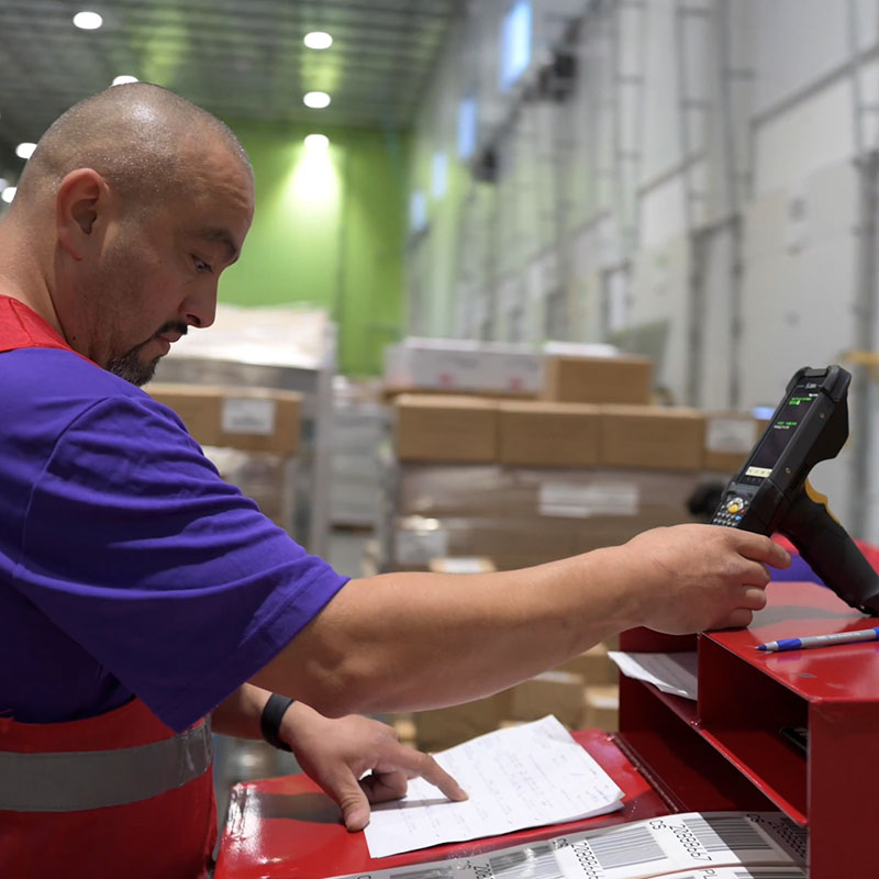 A bald man checking a shipping list in a warehouse